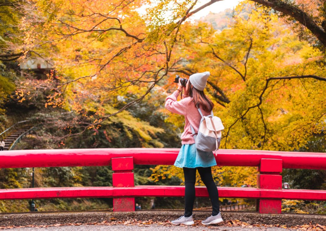 Fiatal nő a japán őszi tájat fotózza