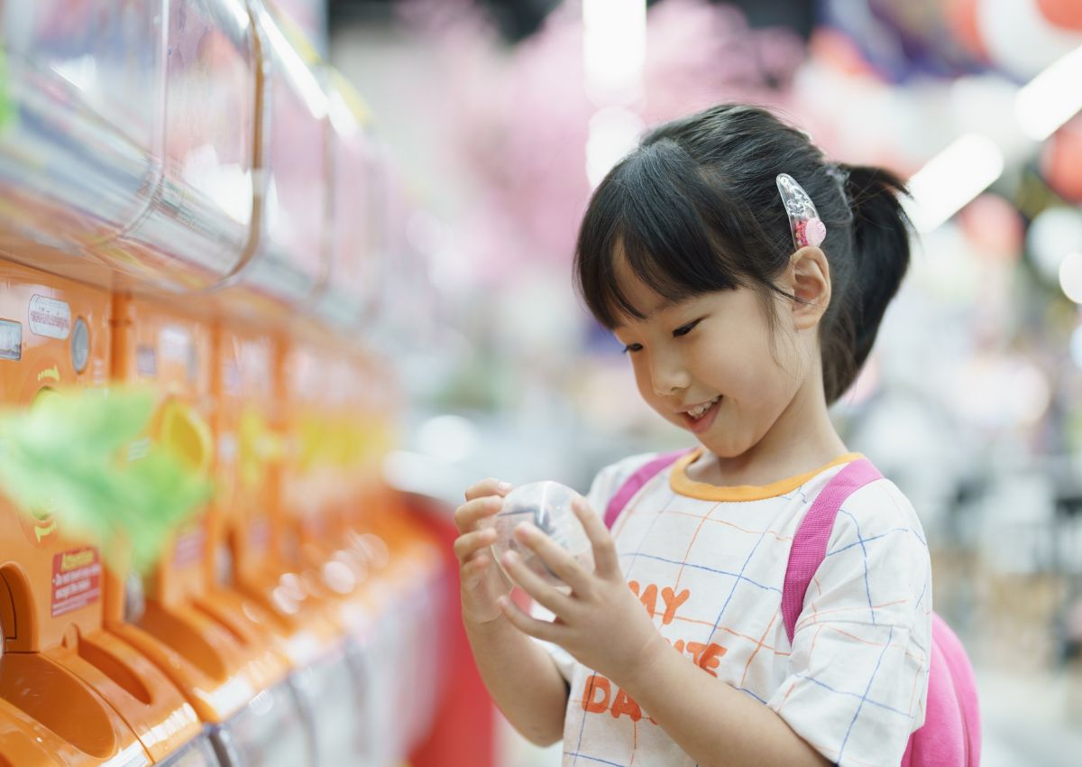 Kislány játszik egy japán gacha játékautomatával.
