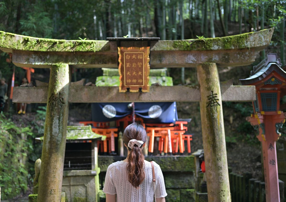 Hölgy a torii kapu előtt a Fushimi Inari-szentélynél, Kiotó, Japán