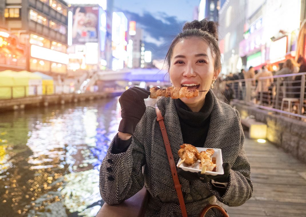 Japán street food ételt fogyasztó nő Oszakában