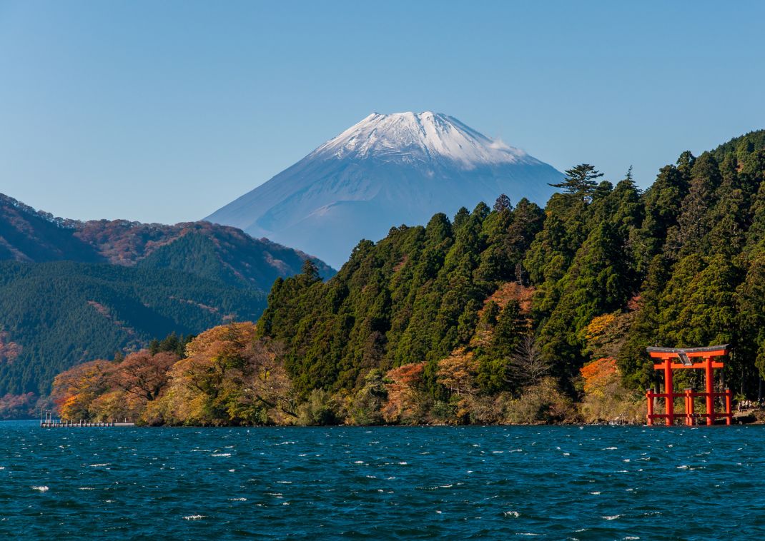  A Fuji-hegy és egy nagy piros torii kapu egy tó partján, kék égbolt alatt