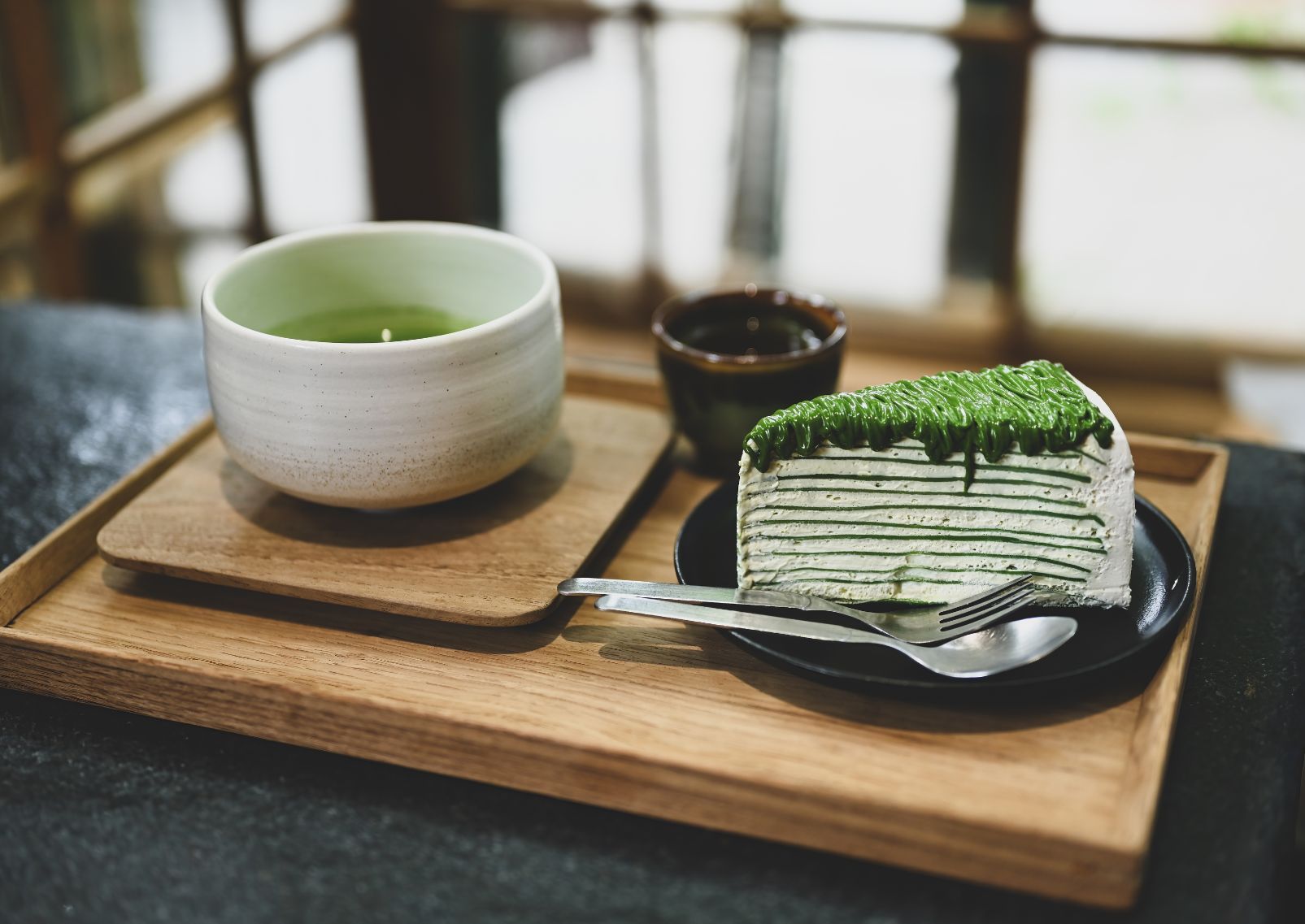 Egy szelet matcha ízesítésű torta genmaicha uji lattéval egy japán hagyományos kerámia tálban