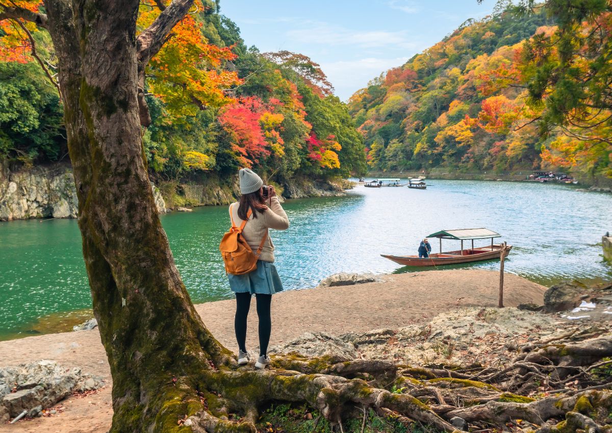 Utazó gyönyörködik Arashiyama őszi színeiben, Kiotóban, Japánban.