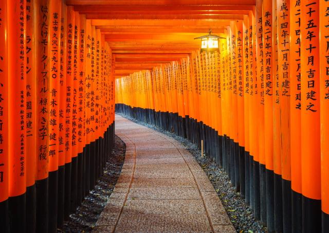 A Fushimi Inari szentély hagyományos, vörösre festett, japán torii-ja, fekete felirattal. Kiotó, Japán.