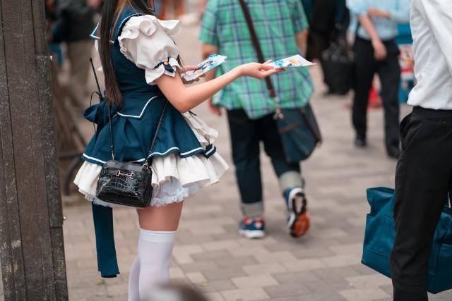 Egy maid cosplayes szórólapokat osztogat a tokiói Akihabarában