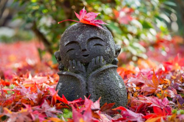 Mosolygós jizo-szobrocska az őszi levelek között, Kiotó 