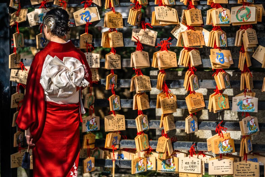 Japán nő imakártyákat olvas egy fatáblán a kiotói Kiyomizu-dera templomban.