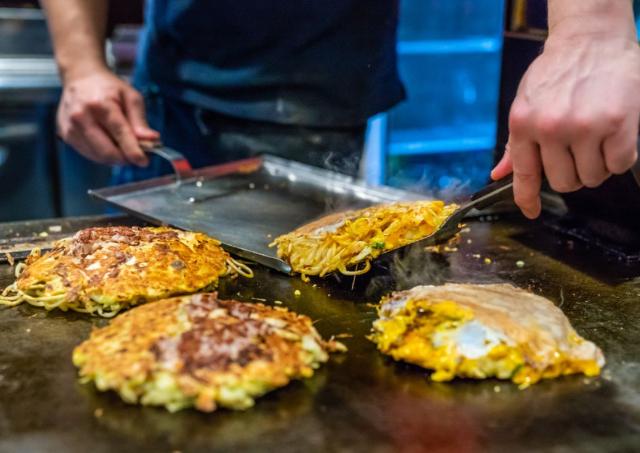 Japán okonomiyaki készül forró sütőlapon