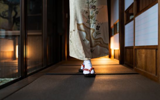 Nő kimonóban sétál egy hagyományos ryokanban tatami szőnyegekkel és shoji ajtókkal