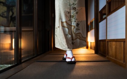 Nő kimonóban sétál egy hagyományos ryokanban tatami szőnyegekkel és shoji ajtókkal