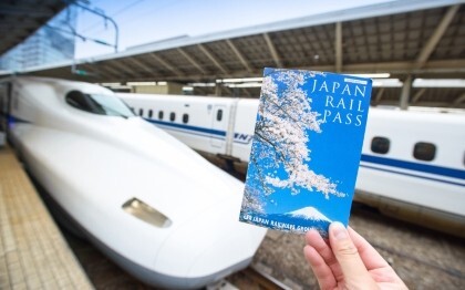Egy Japán vasúti bérletet tartó kéz egy Shinkansen előtt a tokiói pályaudvaron