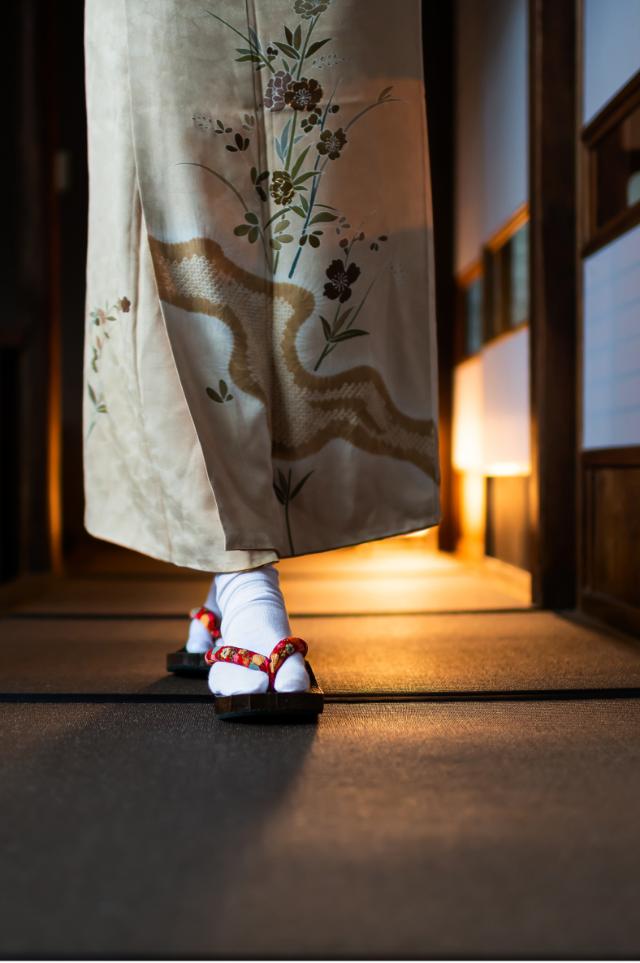 Nő kimonóban sétál egy hagyományos ryokanban tatami szőnyegekkel és shoji ajtókkal
